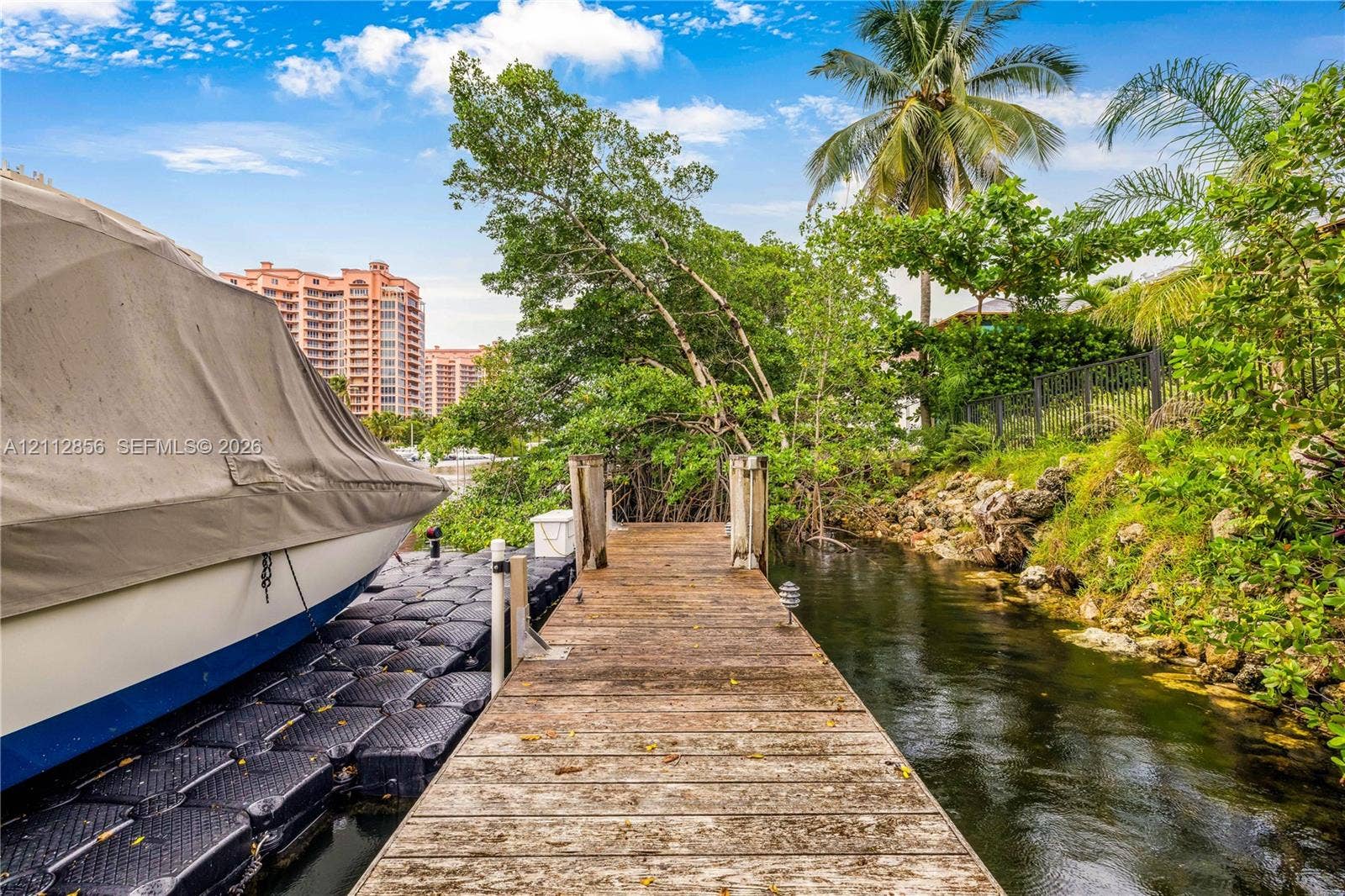 285 Las Brisas Court, Coral Gables, FL 33143 Wood-plank dock featuring modular floating side sections, stone embankment, and metal perimeter fencing