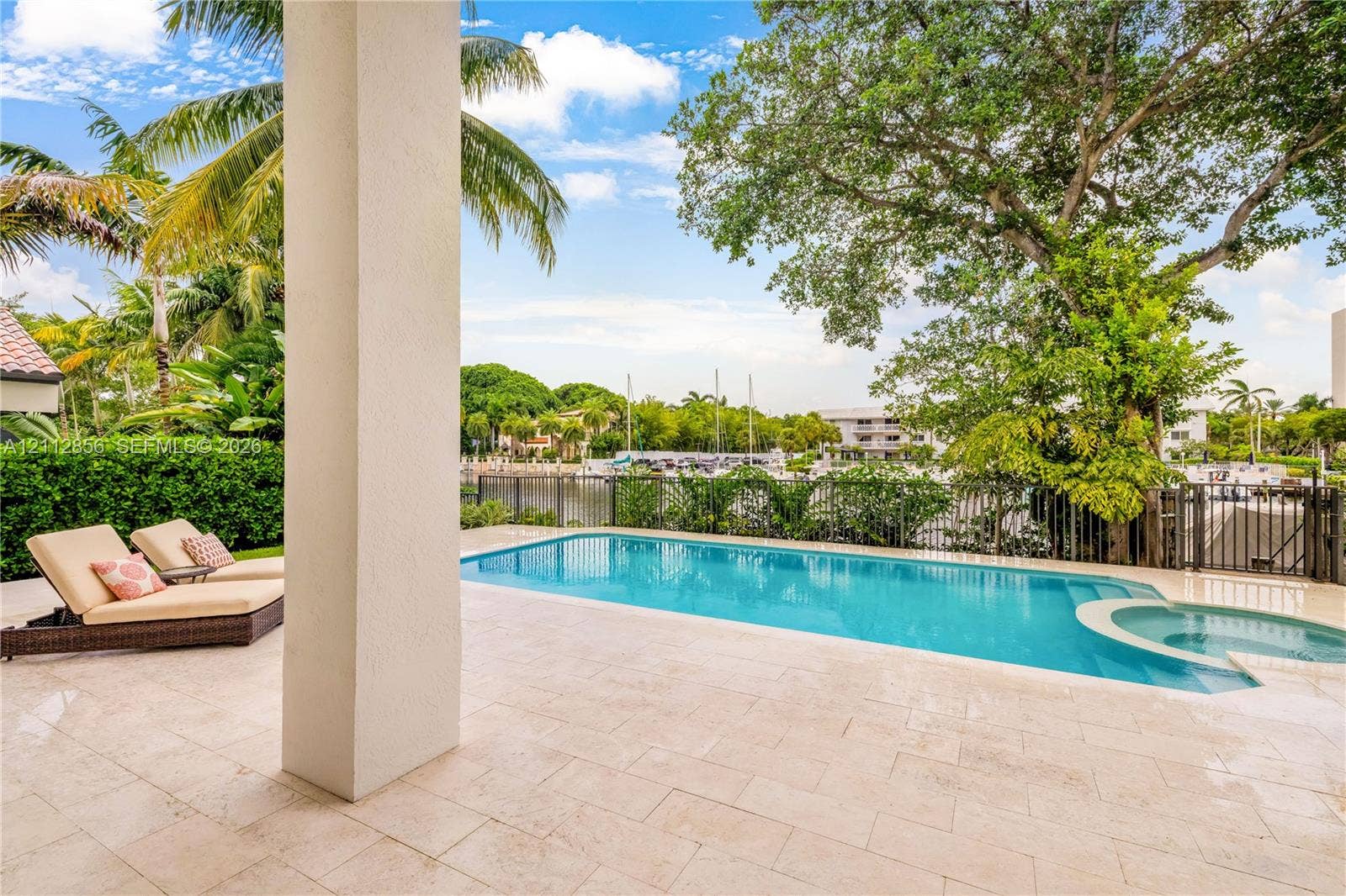 285 Las Brisas Court, Coral Gables, FL 33143 Covered patio with natural stone flooring, swimming pool with integrated spa, and metal perimeter fencing