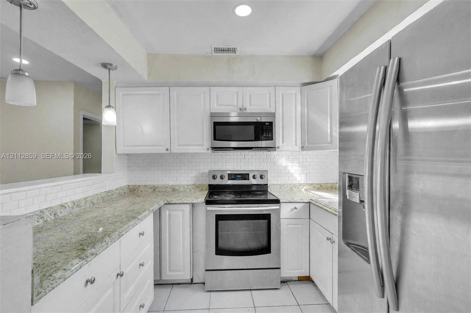 1207 Chateau Park Drive, Fort Lauderdale, FL 33311 Kitchen featuring white cabinetry, stone-finish countertops, subway tile backsplash, stainless steel appliances, and pendant lighting