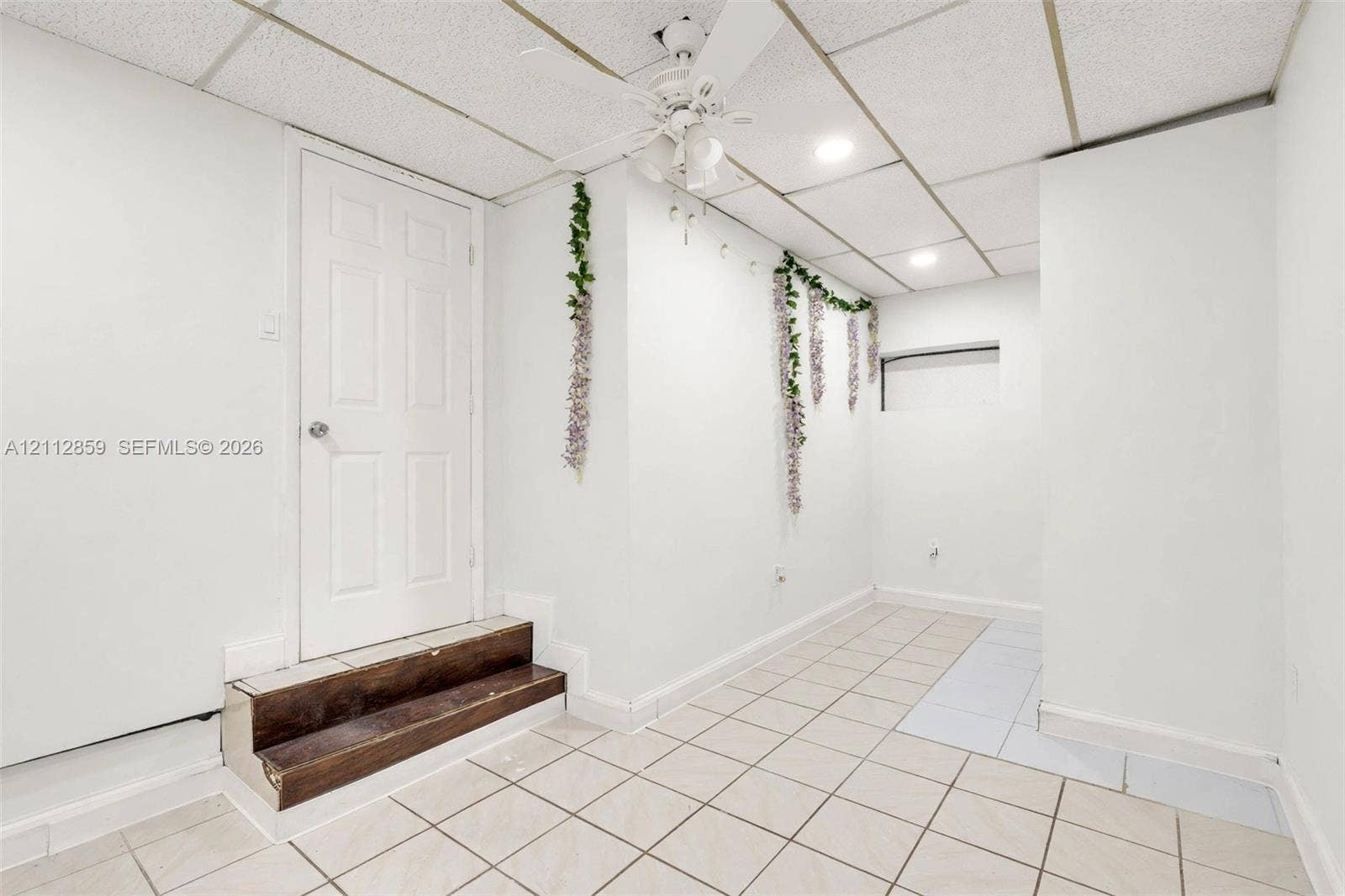 1207 Chateau Park Drive, Fort Lauderdale, FL 33311 Tiled flooring, drop ceiling with recessed lighting, integrated ceiling fan, and wood-finish step leading to a six-panel door