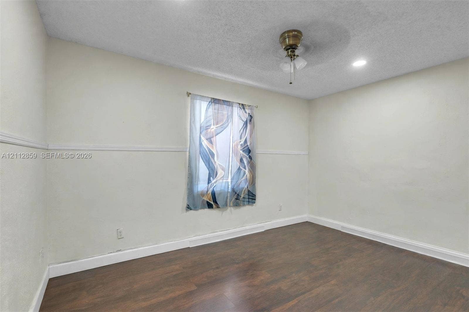 1207 Chateau Park Drive, Fort Lauderdale, FL 33311 Interior space featuring dark wood-finish flooring, neutral walls with chair rail molding, a central ceiling fan with integrated lighting, and a single window
