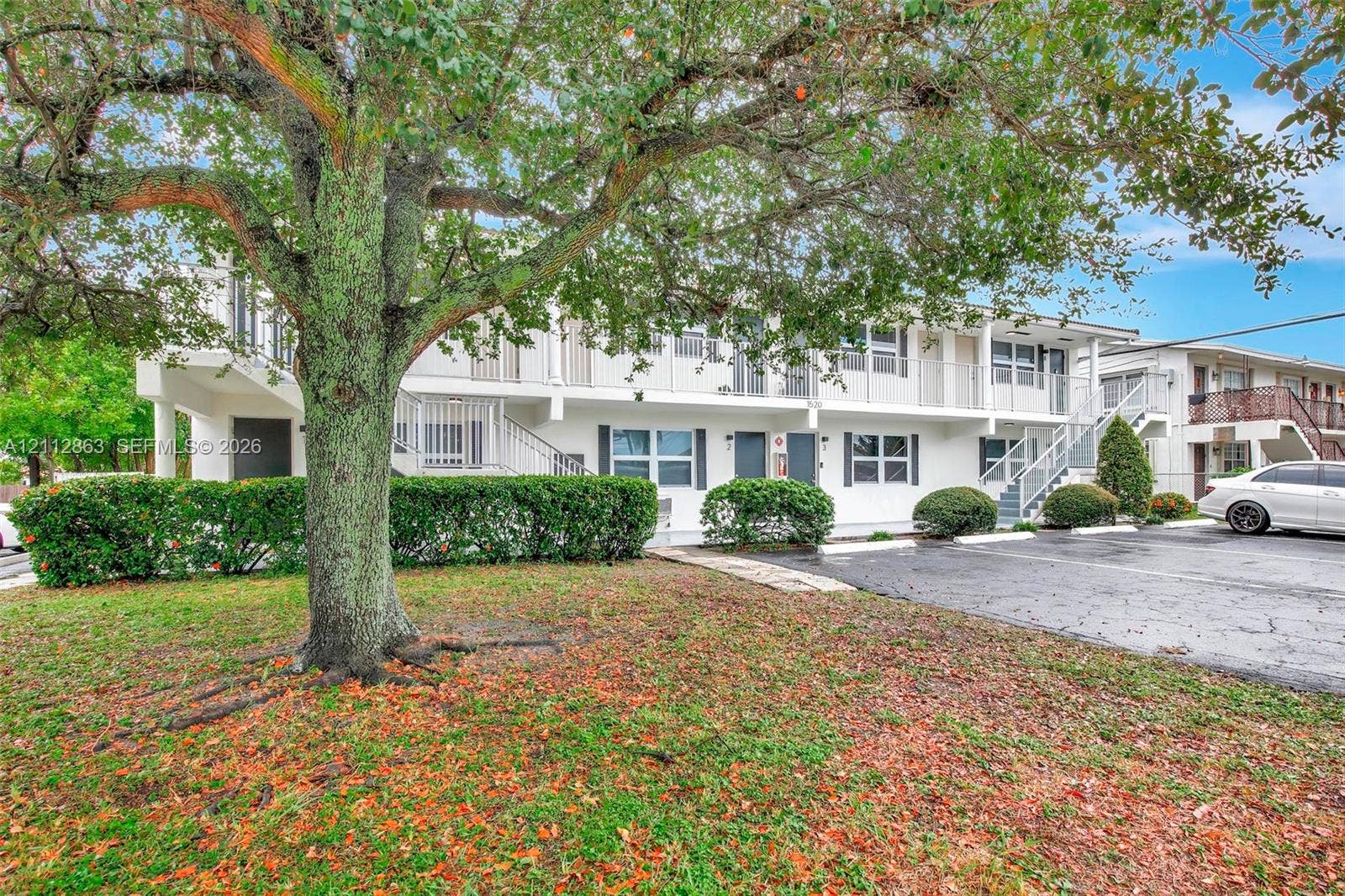 1520 NE 56th Street, #4, Fort Lauderdale, Fort Lauderdale, FL 33334 Two-story multi-unit exterior featuring white stucco siding, metal staircases, second-level railed balconies, and asphalt surface parking