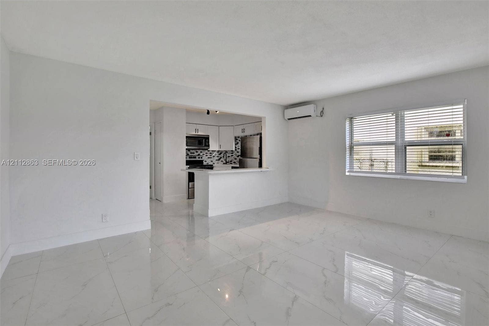 1520 NE 56th Street, #4, Fort Lauderdale, Fort Lauderdale, FL 33334 Polished stone-finish tile flooring, kitchen pass-through with breakfast bar, stainless steel appliances, patterned backsplash, and wall-mounted ductless climate control system