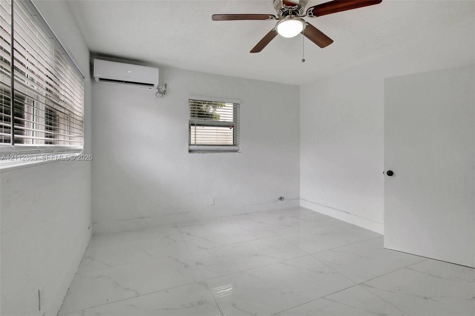1520 NE 56th Street, #4, Fort Lauderdale, Fort Lauderdale, FL 33334 Large-format polished tile flooring, wall-mounted ductless air conditioning unit, ceiling fan with integrated lighting, and horizontal window blinds