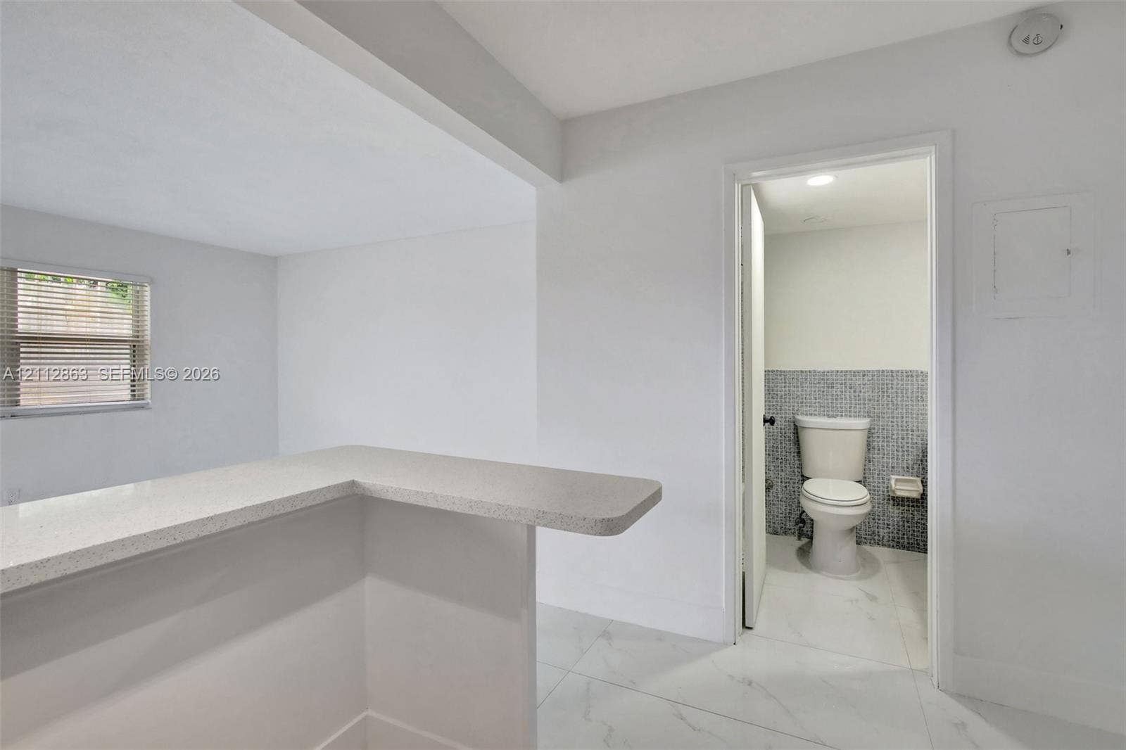 1520 NE 56th Street, #4, Fort Lauderdale, Fort Lauderdale, FL 33334 Neutral-toned kitchen counter with a matte finish, white porcelain tile flooring, and a bathroom featuring mosaic tile wall accents