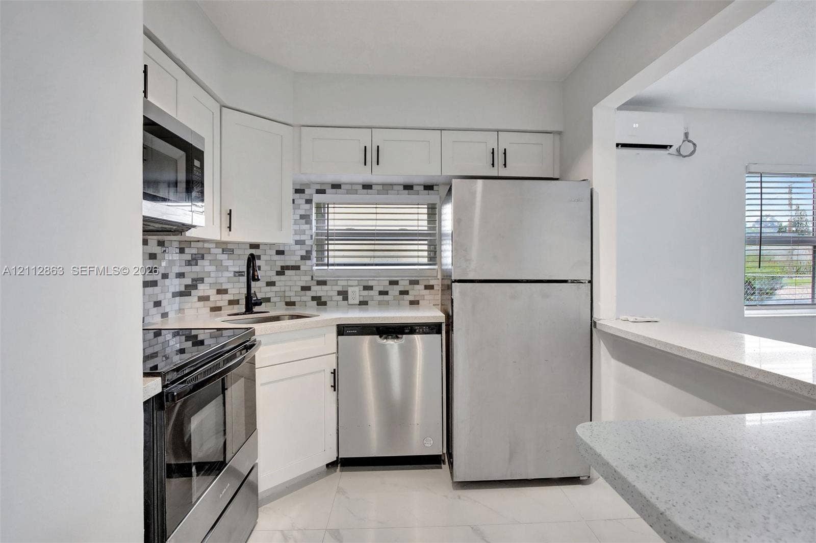 1520 NE 56th Street, #4, Fort Lauderdale, Fort Lauderdale, FL 33334 Kitchen featuring white Shaker-style cabinetry, stainless steel appliances, multi-toned mosaic tile backsplash, solid-surface countertops, and tile flooring