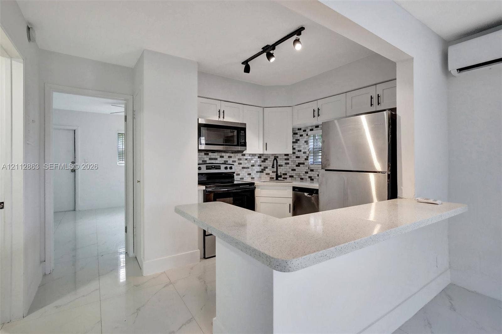 1520 NE 56th Street, #4, Fort Lauderdale, Fort Lauderdale, FL 33334 Kitchen featuring white cabinetry, quartz countertops with a breakfast bar, stone-tile backsplash, stainless steel appliances, and track lighting