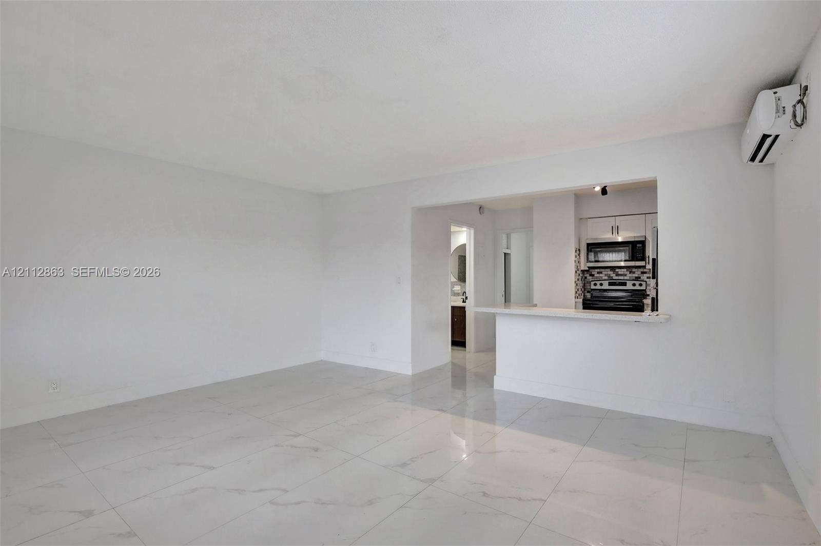 1520 NE 56th Street, #4, Fort Lauderdale, Fort Lauderdale, FL 33334 Open-concept interior featuring large-format tile flooring, a breakfast bar, and a wall-mounted ductless air conditioning unit
