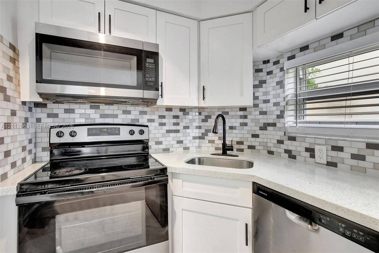 1520 NE 56th Street, #4, Fort Lauderdale, Fort Lauderdale, FL 33334 Kitchen featuring white shaker-style cabinetry, a multi-tonal rectangular tile backsplash, stainless steel appliances, light-colored countertops, and a matte black gooseneck faucet