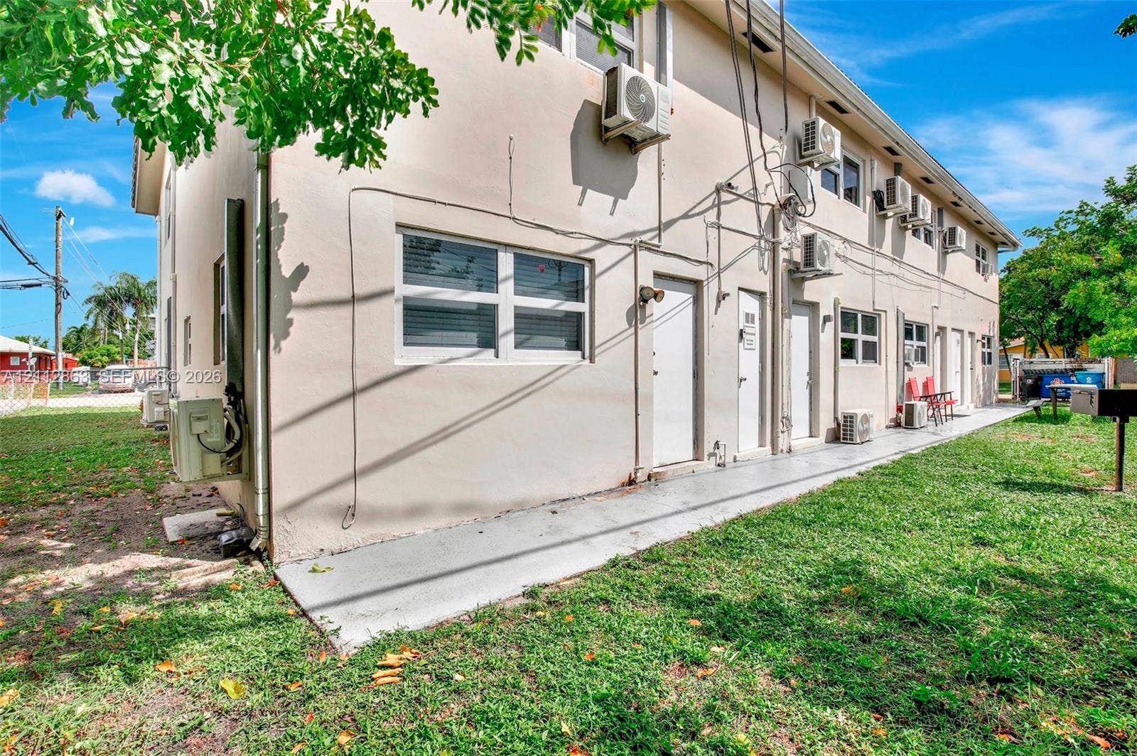 1520 NE 56th Street, #4, Fort Lauderdale, Fort Lauderdale, FL 33334 Stucco exterior building featuring multiple wall-mounted air conditioning units, sliding windows, and a poured concrete walkway