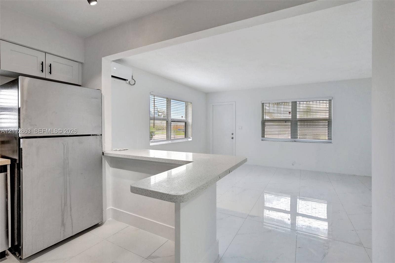 1520 NE 56th Street, #4, Fort Lauderdale, Fort Lauderdale, FL 33334 Kitchen featuring an L-shaped breakfast bar with quartz countertop, high-gloss tile flooring, stainless steel refrigerator, and white cabinetry