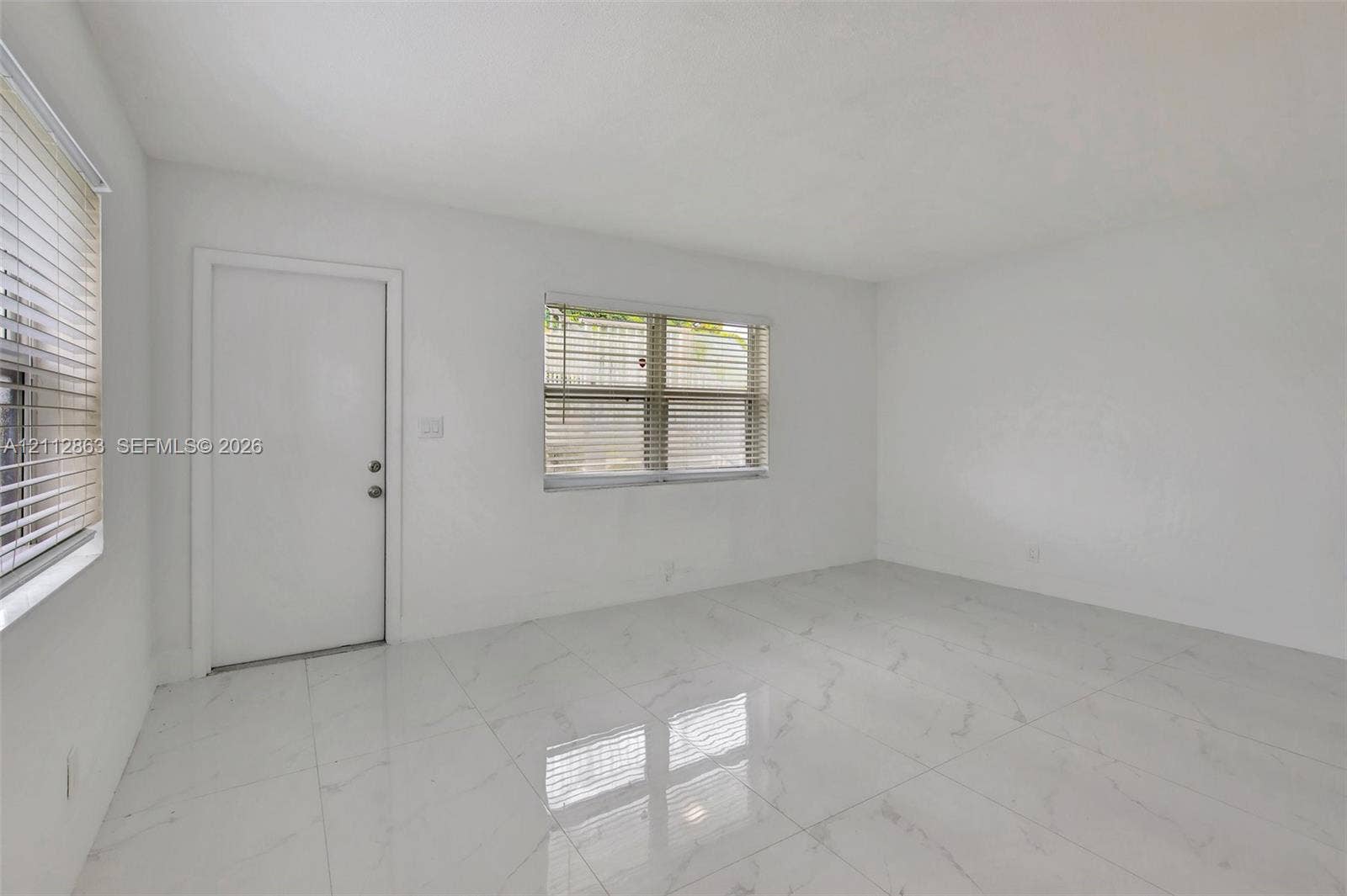 1520 NE 56th Street, #4, Fort Lauderdale, Fort Lauderdale, FL 33334 Neutral interior space featuring polished tile flooring, white wall finishes, and two windows with horizontal blinds