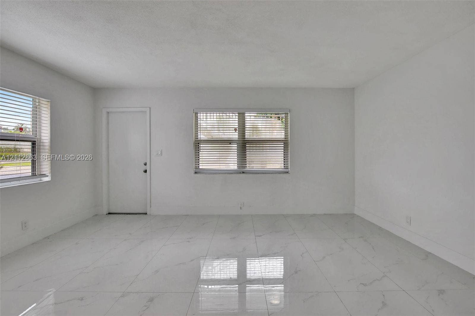 1520 NE 56th Street, #4, Fort Lauderdale, Fort Lauderdale, FL 33334 Open-concept room featuring large-format tile flooring with a veined pattern, neutral wall finishes, and multiple windows with horizontal blinds
