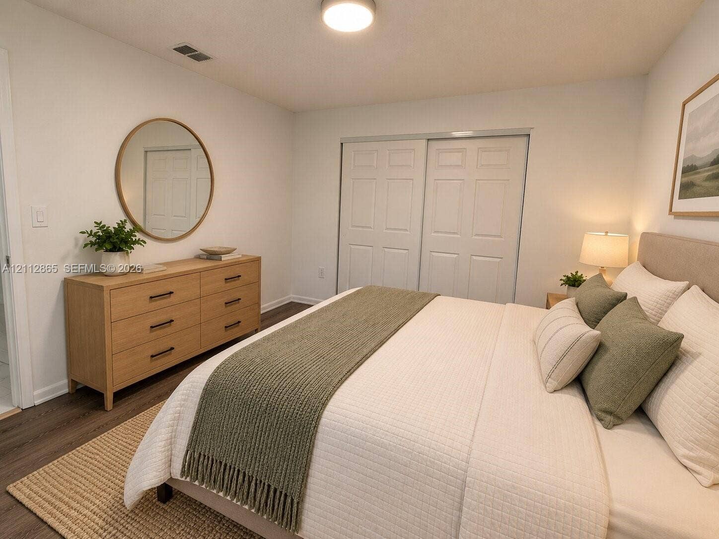 Wood-finish flooring, neutral wall tones, and white sliding-panel closet doors