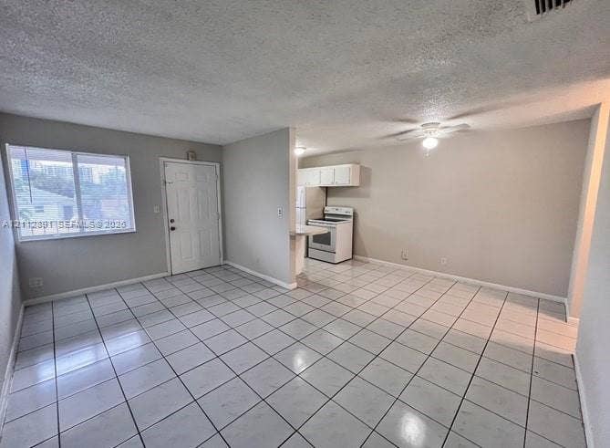2150 Madison Street, #26, Hollywood, Hollywood, FL 33020 Open-concept area featuring white ceramic tile flooring, a ceiling-mounted light fixture, a large window, and an eat-in kitchen area with white cabinetry