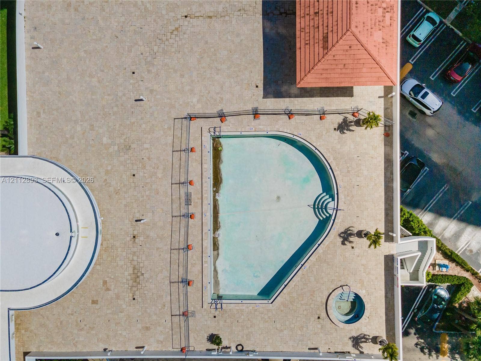 20515 E Country Club Drive, #1048, Aventura, FL 33180 Aerial view of a sprawling pool deck featuring stone-tiled hardscaping, an in-ground swimming pool, a separate circular spa, and a covered pavilion structure