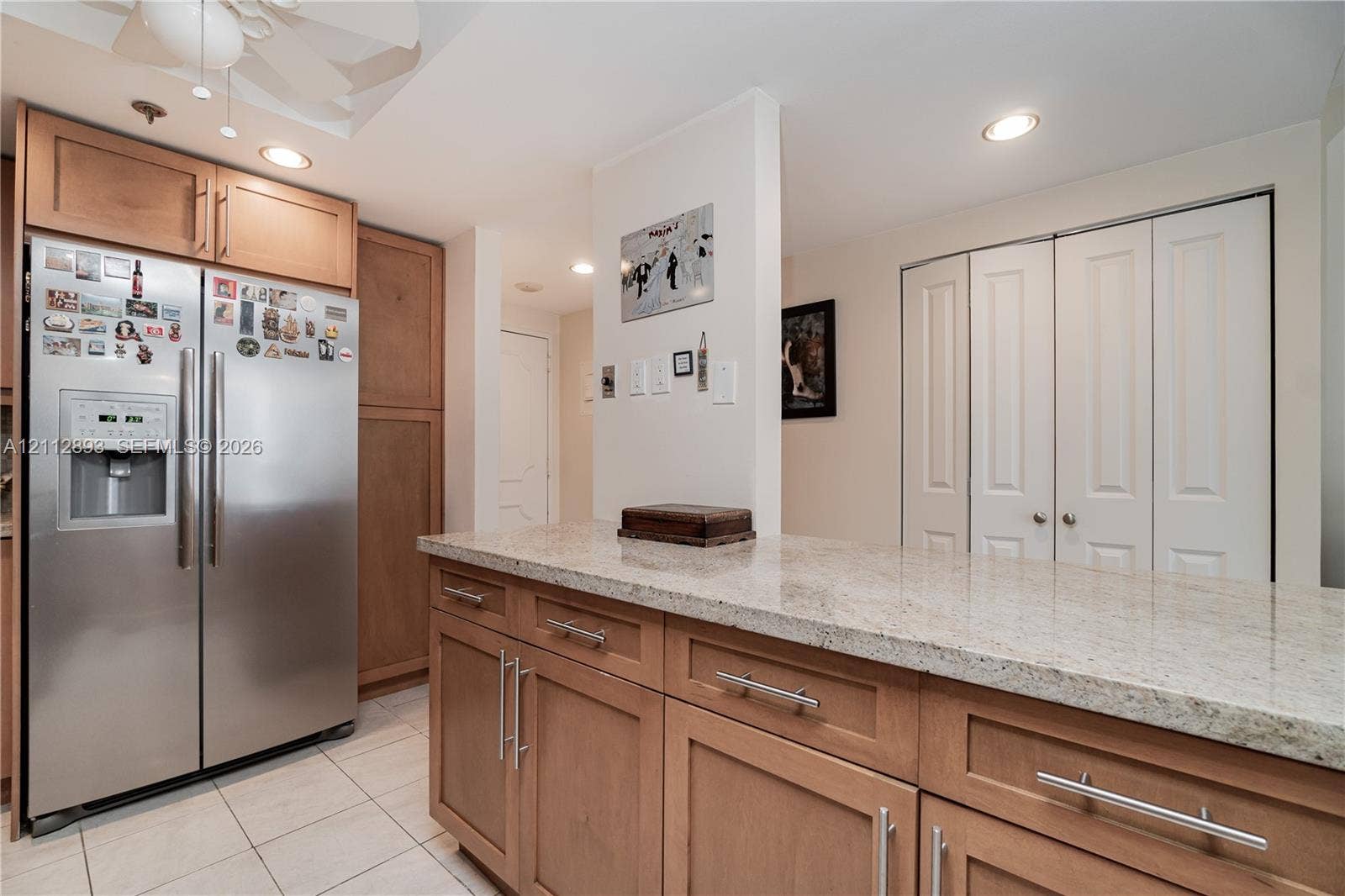 20515 E Country Club Drive, #1048, Aventura, FL 33180 Kitchen featuring wood cabinetry, stone-finish countertops, stainless steel refrigerator, recessed lighting, and white bifold closet doors