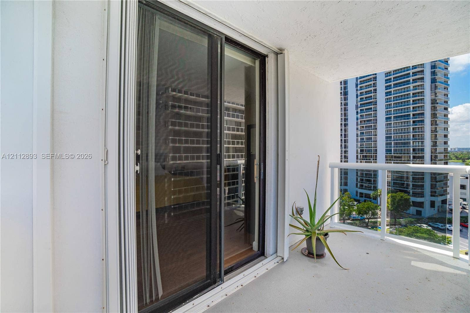 20515 E Country Club Drive, #1048, Aventura, FL 33180 Covered balcony featuring a white metal railing and sliding glass door entrance