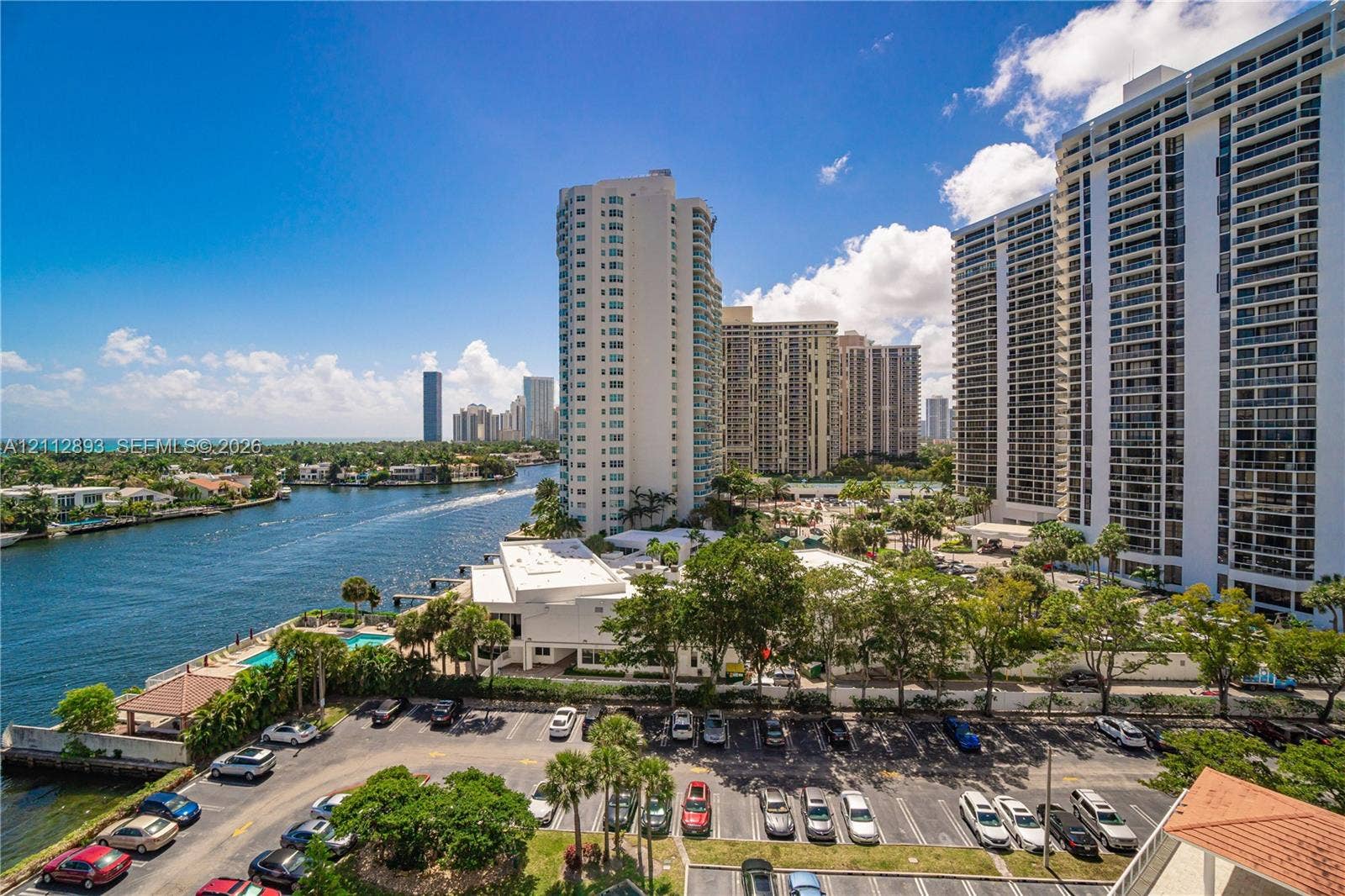 20515 E Country Club Drive, #1048, Aventura, FL 33180 High-rise vantage point featuring a waterway, mature palm trees, paved parking area, and coastal landscape