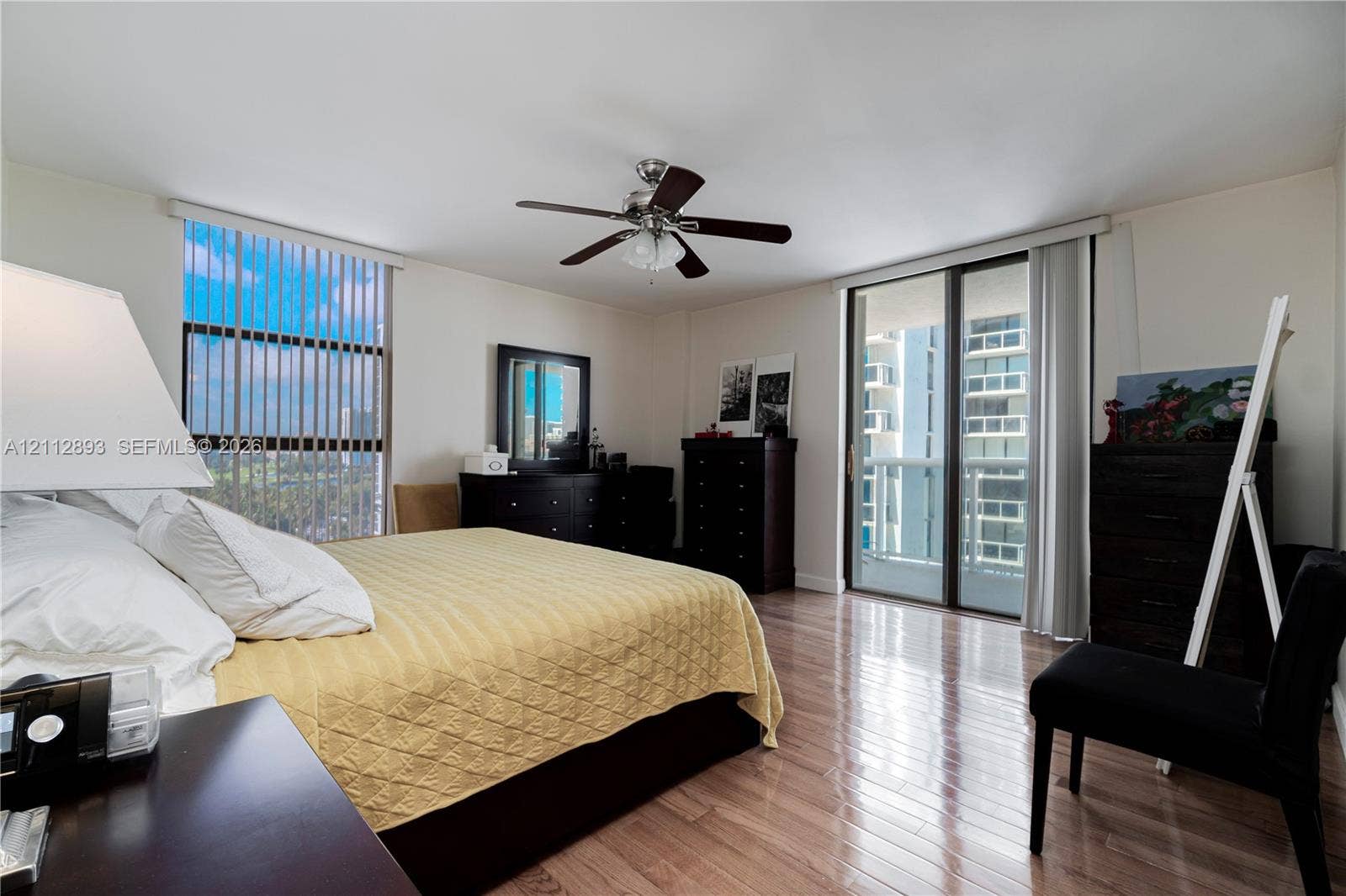 20515 E Country Club Drive, #1048, Aventura, FL 33180 Wood-finish flooring, ceiling fan with integrated lighting, large vertical window with blinds, and sliding glass door with access to a balcony