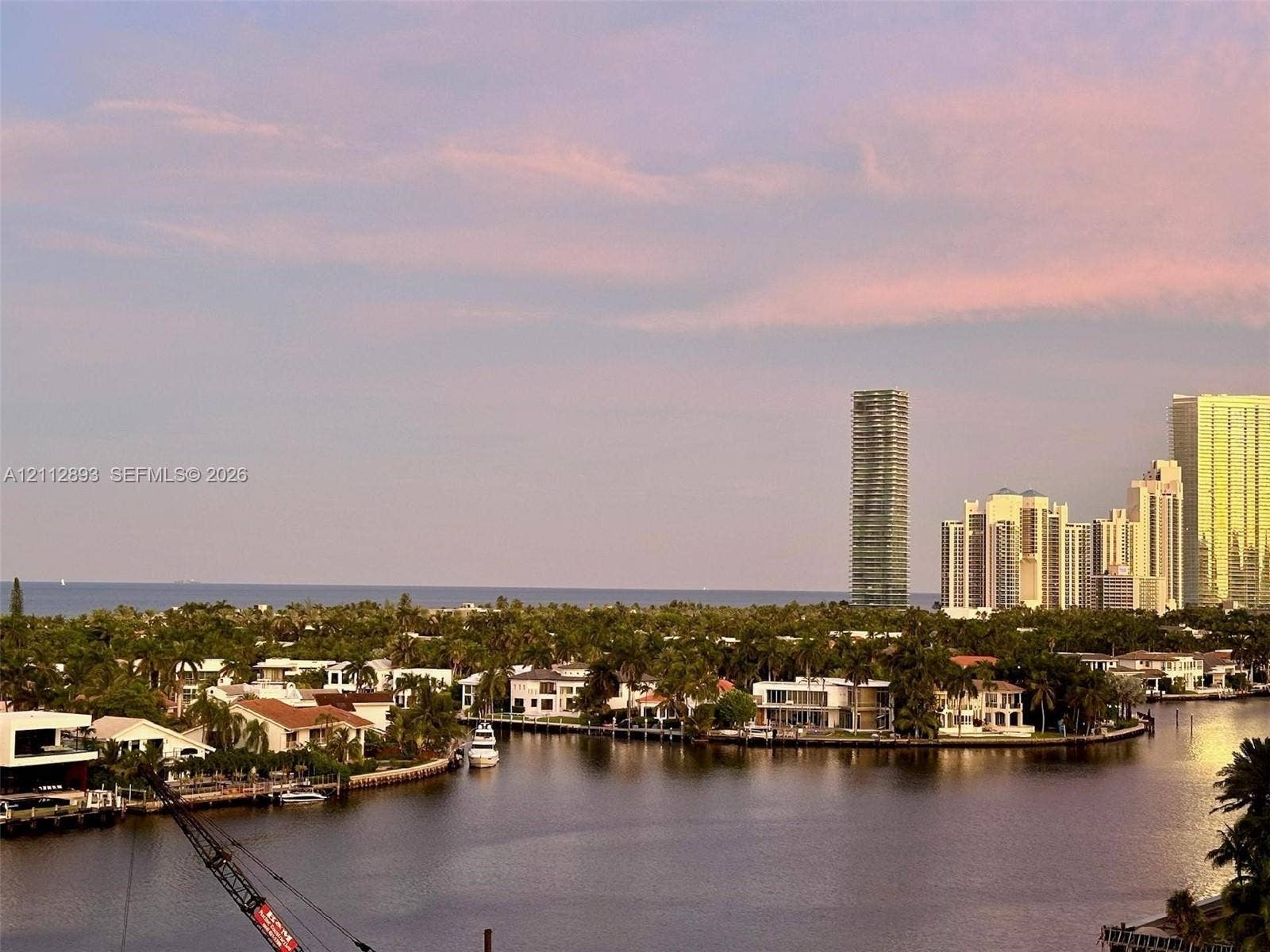 20515 E Country Club Drive, #1048, Aventura, FL 33180 Waterfront landscape featuring a winding canal, mature palms, residential structures, and a distant coastal horizon