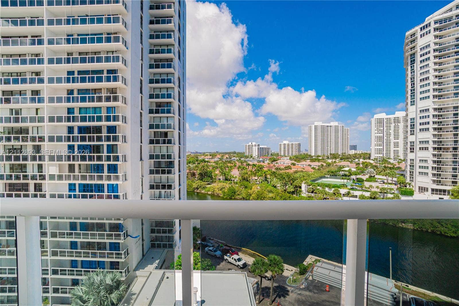 20515 E Country Club Drive, #1048, Aventura, FL 33180 Balcony with glass panel railing overlooking a waterway and urban skyline