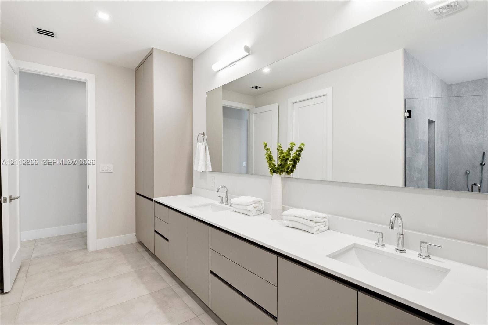 2747 SW 23rd Terrace, Miami, FL 33145 Extended vanity featuring flat-panel cabinetry, light-toned solid surface countertops, dual undermount sinks, and a large-format vanity mirror with integrated linear lighting