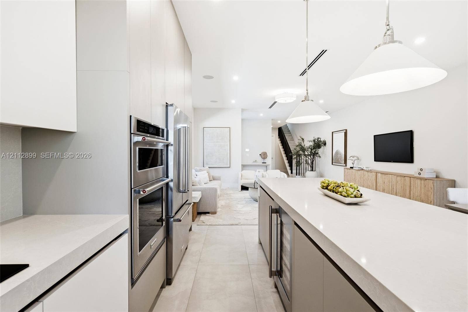 2747 SW 23rd Terrace, Miami, FL 33145 Kitchen featuring flat-panel cabinetry, a spacious island with a solid surface countertop, stainless steel double wall ovens, a side-by-side refrigerator, and large-format tile flooring