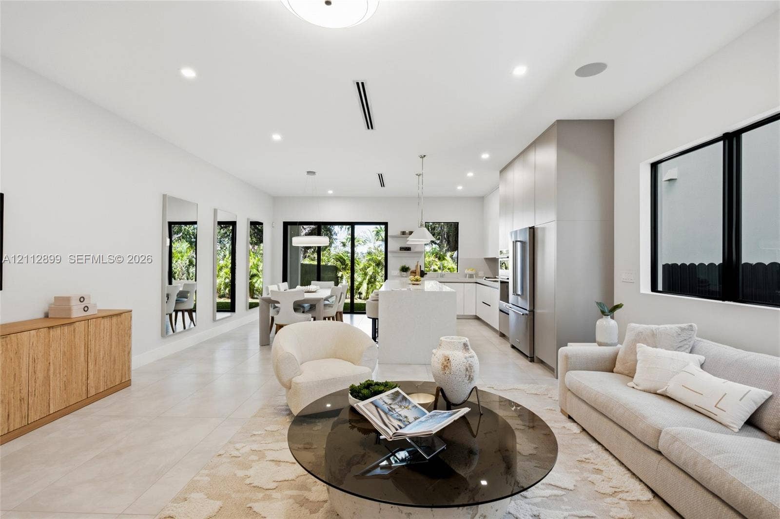 2747 SW 23rd Terrace, Miami, FL 33145 Open-concept interior featuring large-format tile flooring, recessed ceiling lighting, custom flat-panel cabinetry, a central kitchen island with waterfall-edge countertop, and sliding glass doors