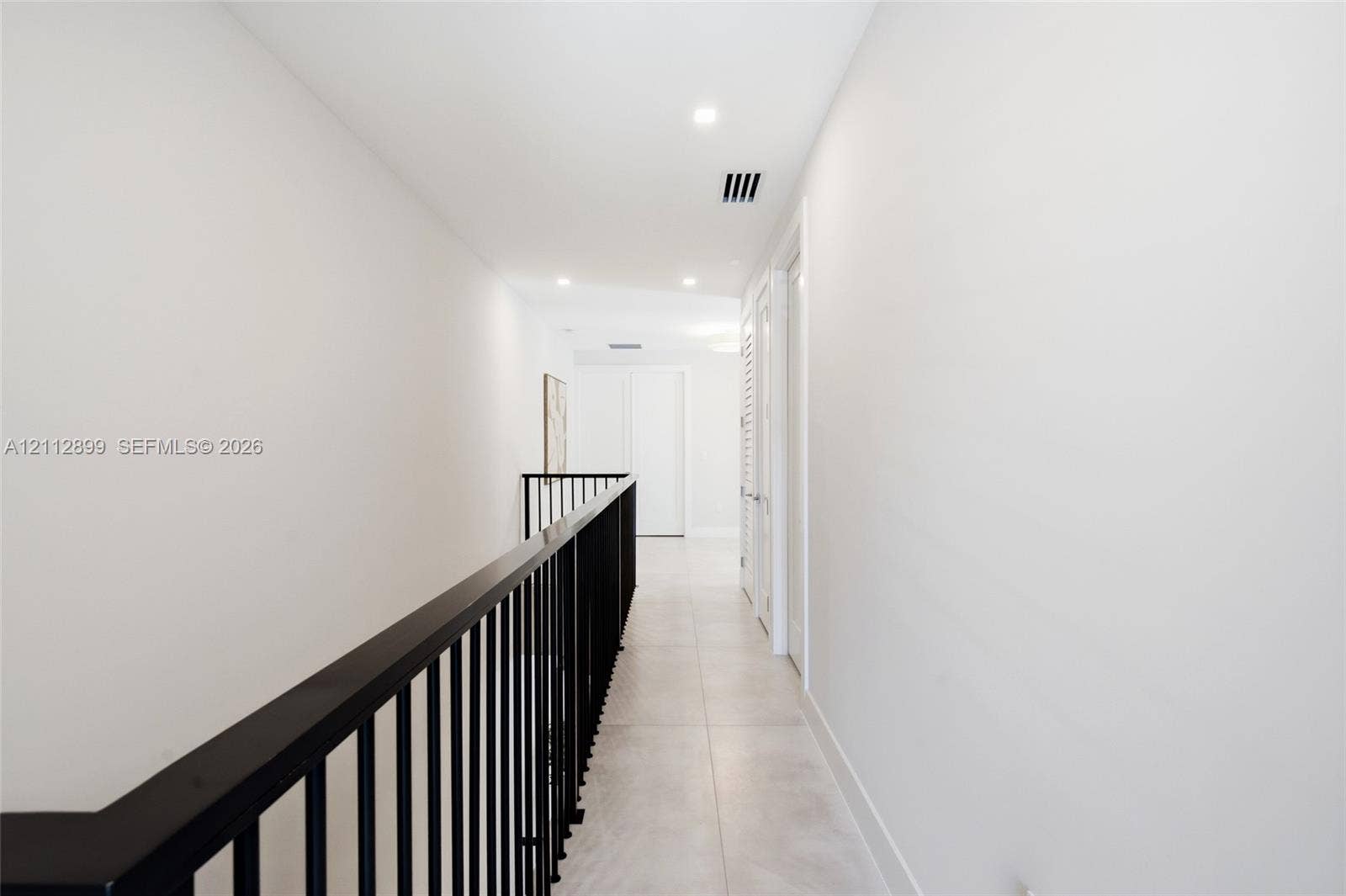 2747 SW 23rd Terrace, Miami, FL 33145 Hallway featuring large-format tile flooring, matte black metal railing, and recessed ceiling lighting