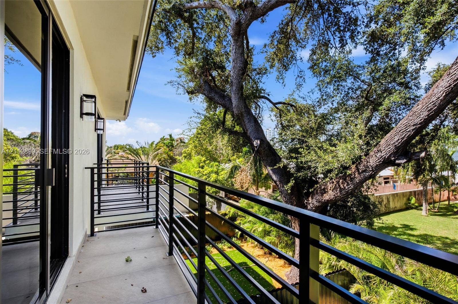 2747 SW 23rd Terrace, Miami, FL 33145 Covered balcony featuring matte black metal railings, concrete flooring, and wall-mounted exterior lighting