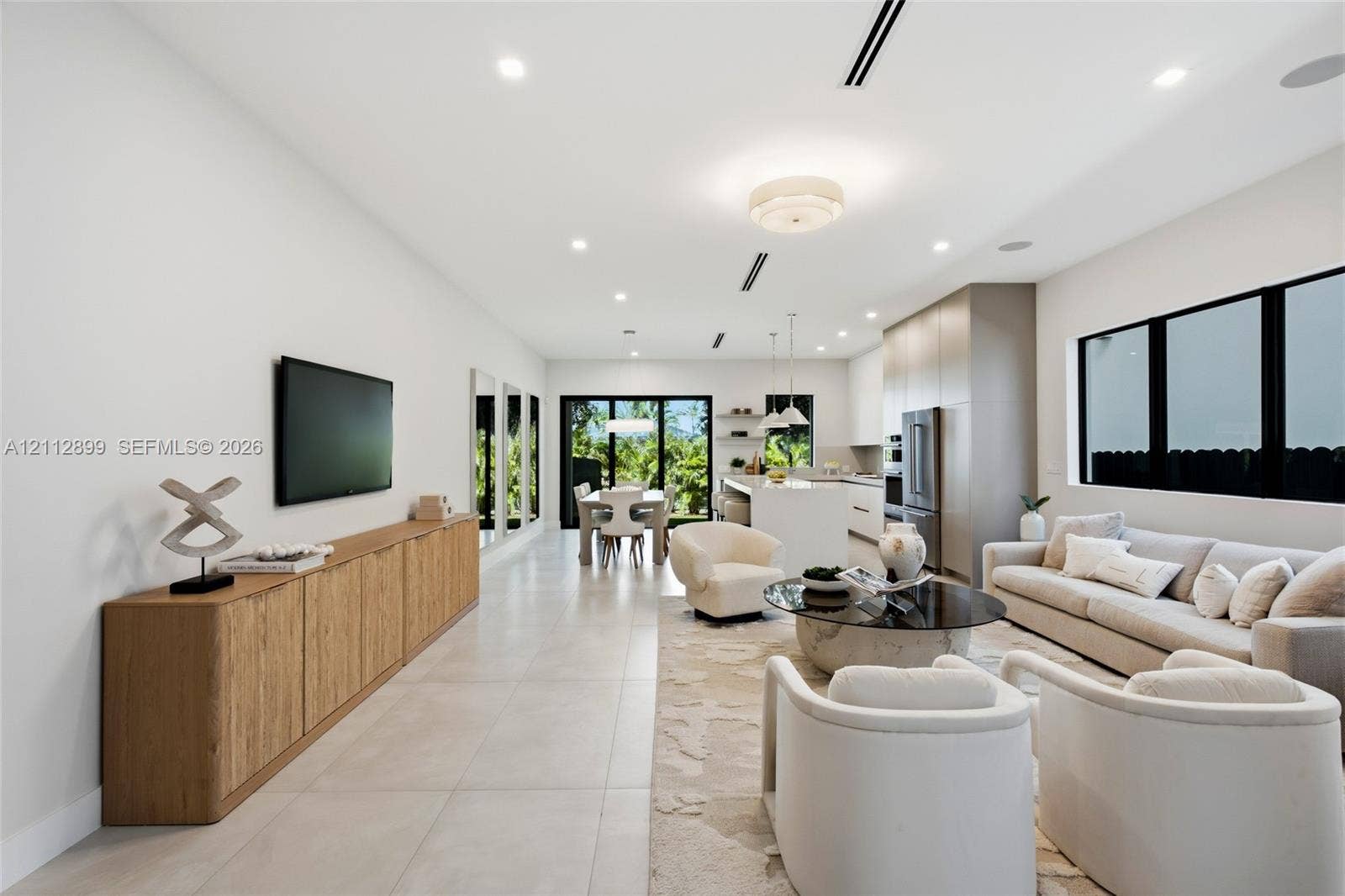 2747 SW 23rd Terrace, Miami, FL 33145 Open-concept living space featuring large-format tile flooring, recessed lighting, expansive glass sliding doors, built-in cabinetry, and a kitchen island with stone countertops
