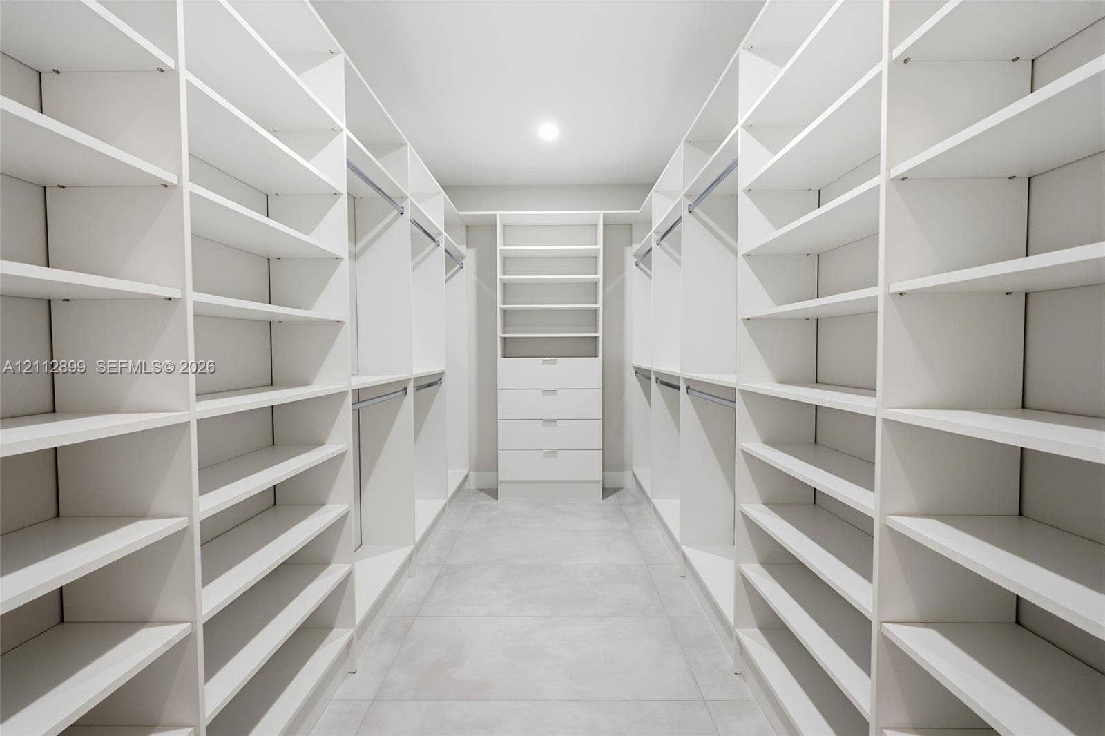 2747 SW 23rd Terrace, Miami, FL 33145 Walk-in closet featuring extensive built-in white shelving, integrated clothing rods, a central drawer bank, and tile flooring