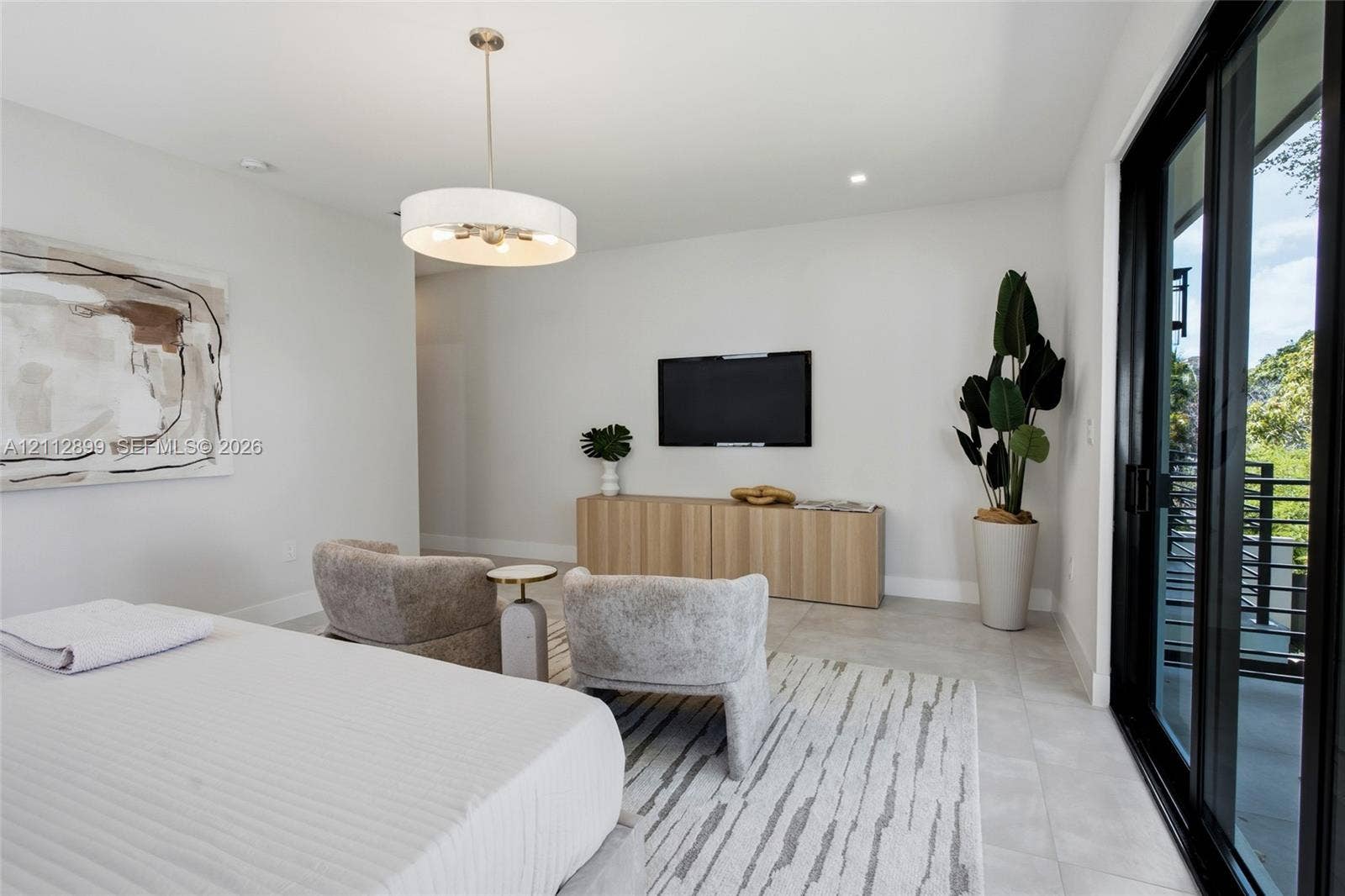 2747 SW 23rd Terrace, Miami, FL 33145 Neutral-toned interior featuring large-format tile flooring, a contemporary drum pendant light fixture, and black-framed sliding glass doors opening to an exterior balcony