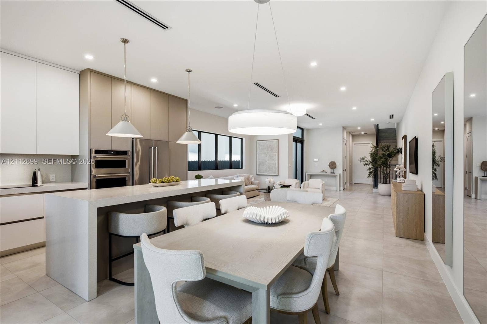 2747 SW 23rd Terrace, Miami, FL 33145 Open-concept kitchen featuring flat-panel cabinetry, a waterfall-edge stone island, built-in double ovens, and large-format tile flooring