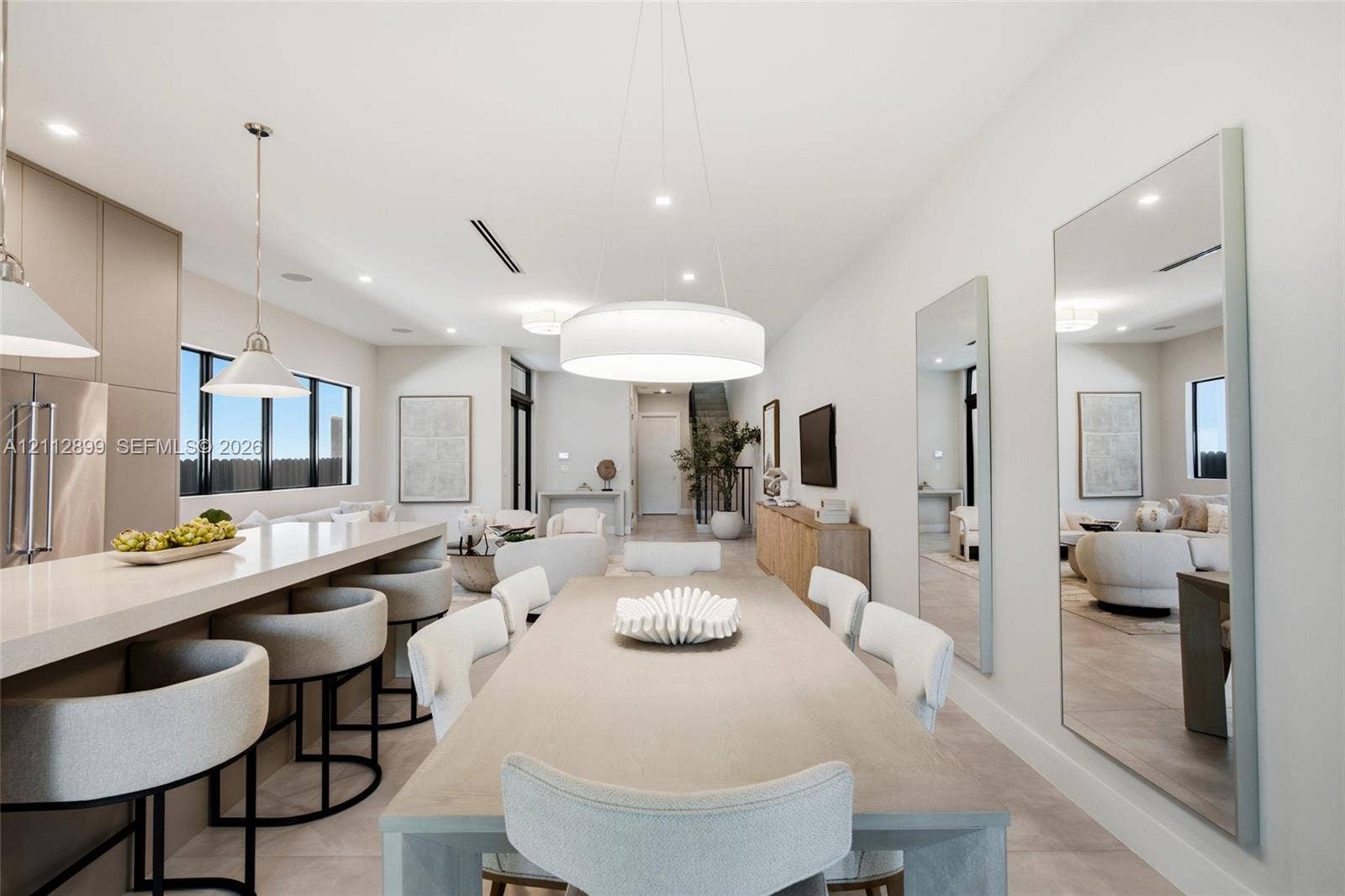 2747 SW 23rd Terrace, Miami, FL 33145 Open-concept interior featuring a kitchen island with stone countertop, large-scale drum pendant lighting, flush-mount recessed ceiling lights, and wall-to-wall mirrors