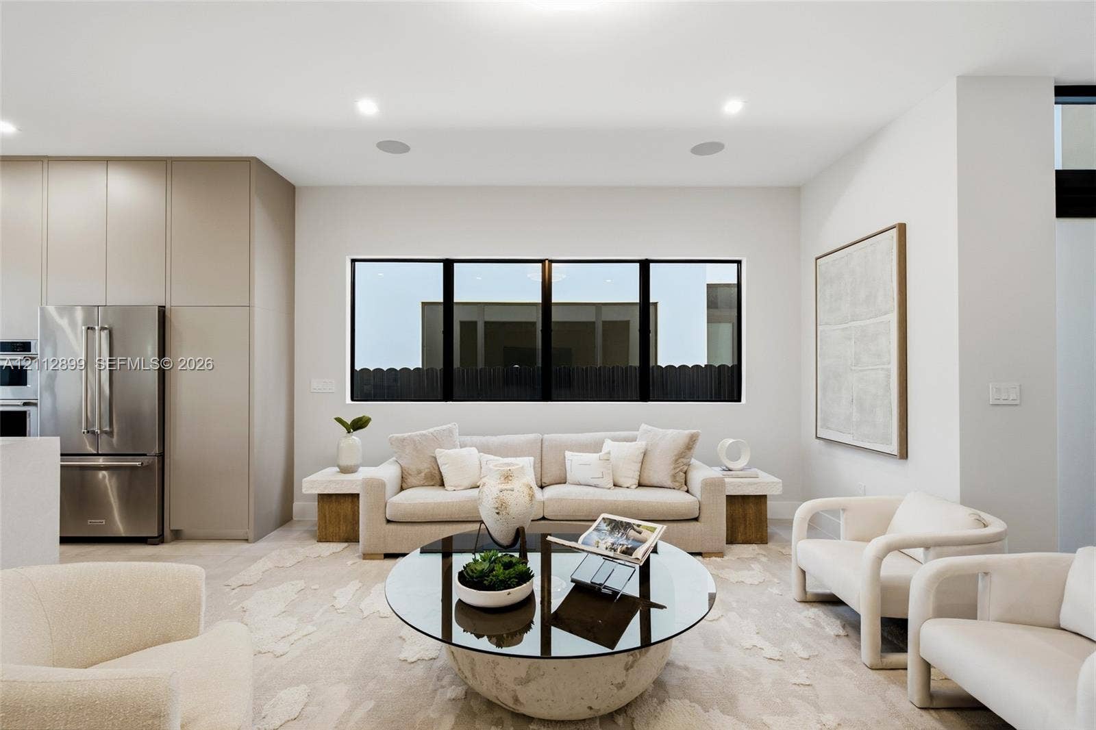 2747 SW 23rd Terrace, Miami, FL 33145 Open-concept living space featuring floor-to-ceiling cabinetry, stainless steel refrigerator, recessed lighting, and expansive tripartite black-framed window