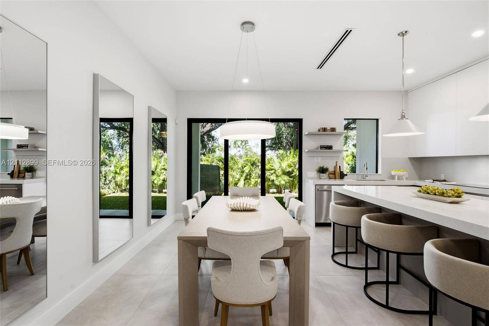 2747 SW 23rd Terrace, Miami, FL 33145 Modern kitchen featuring flat-panel cabinetry, a quartz waterfall island, large-format tile flooring, integrated linear lighting, and floor-to-ceiling glass sliding doors