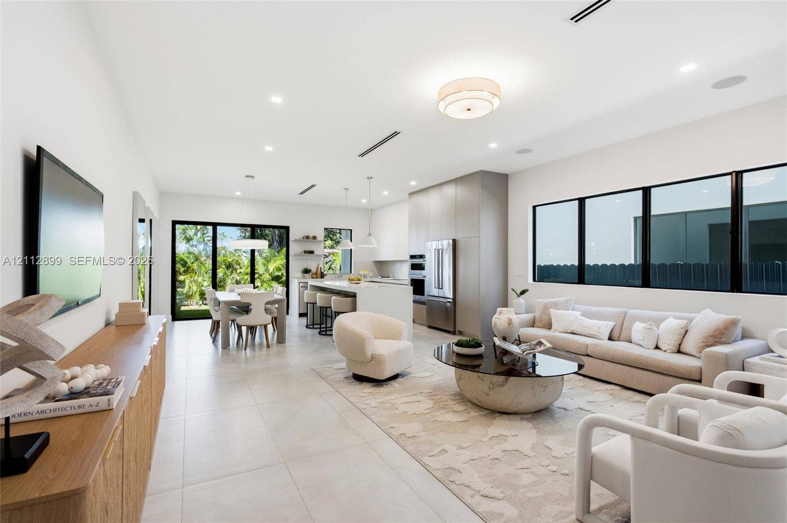 2747 SW 23rd Terrace, Miami, FL 33145 Open-concept interior featuring large-format tile flooring, recessed ceiling lighting, built-in kitchen cabinetry, stainless steel appliances, and black-framed windows