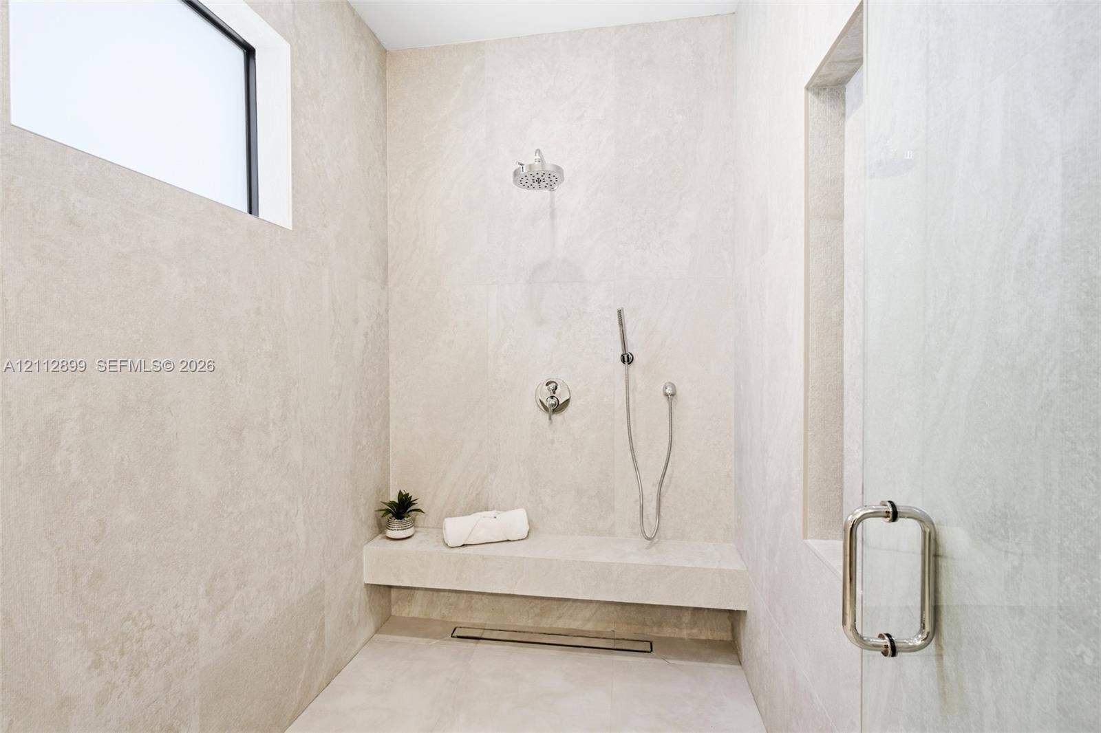 2747 SW 23rd Terrace, Miami, FL 33145 Walk-in shower featuring floor-to-ceiling stone-finish tile, a built-in stone bench, overhead rainfall showerhead, adjustable handheld shower wand, and glass enclosure door