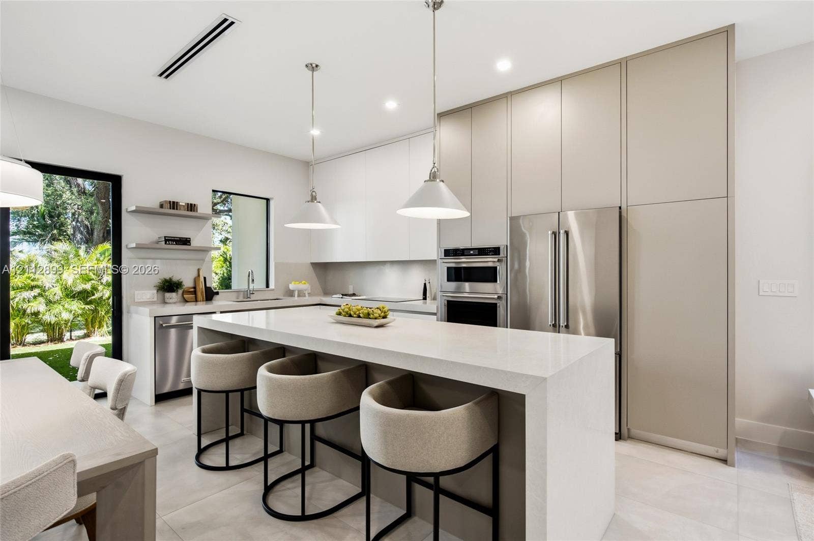 2747 SW 23rd Terrace, Miami, FL 33145 Contemporary kitchen featuring floor-to-ceiling flat-panel cabinetry, a waterfall-edge stone island, built-in stainless steel appliances, and dual pendant lighting