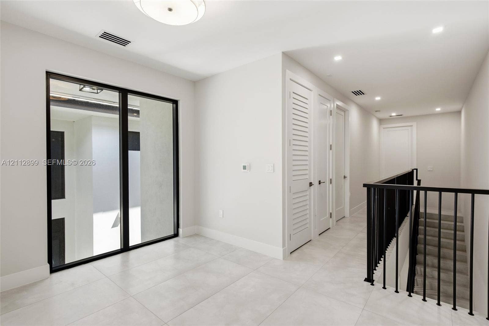 2747 SW 23rd Terrace, Miami, FL 33145 Large-format tile flooring, black-framed floor-to-ceiling glass window, recessed lighting, and a staircase with a black metal railing