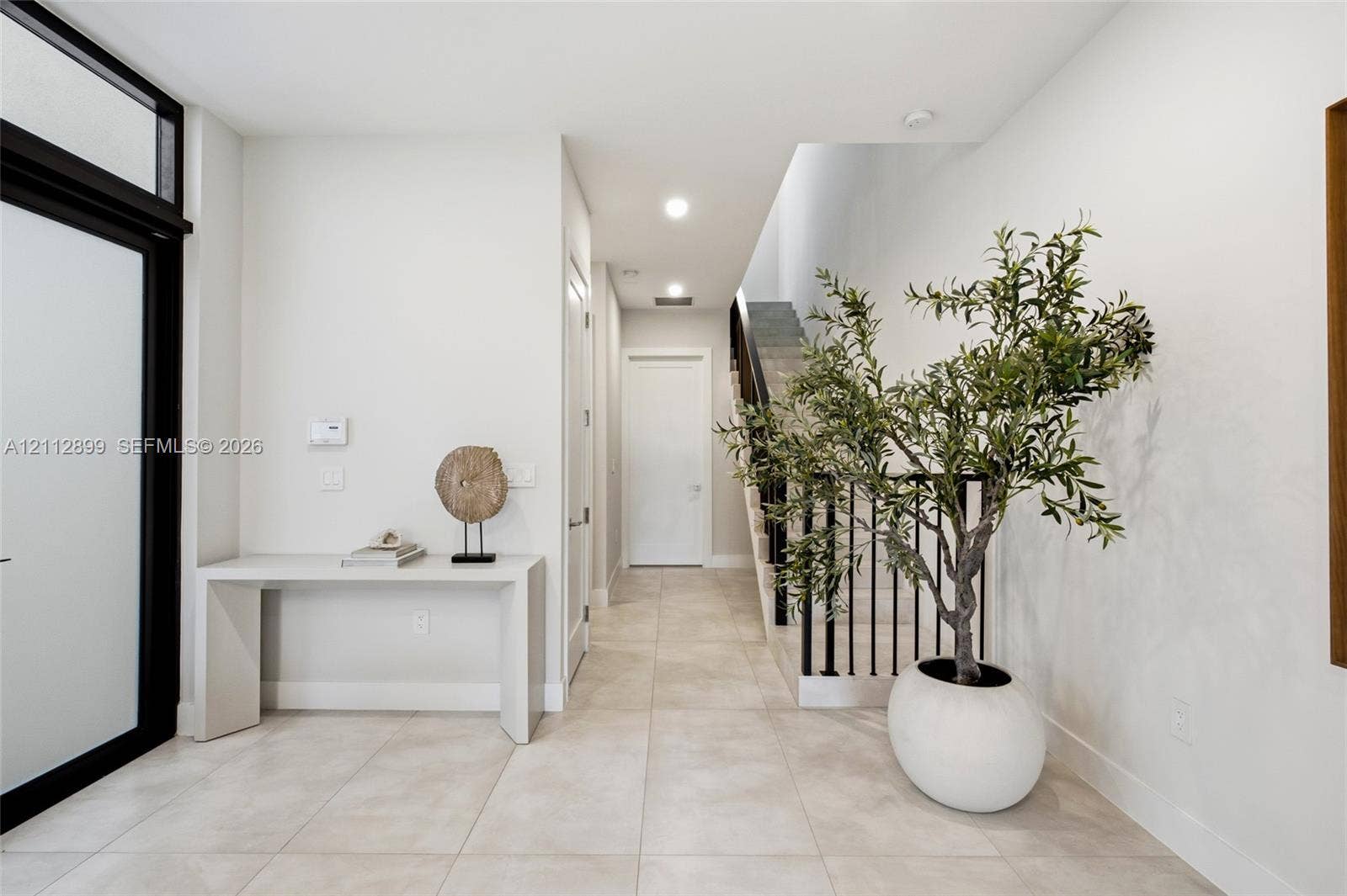 2747 SW 23rd Terrace, Miami, FL 33145 Entryway featuring large-format tile flooring, a glass-paneled front door with black trim, recessed lighting, and a staircase with black metal balusters