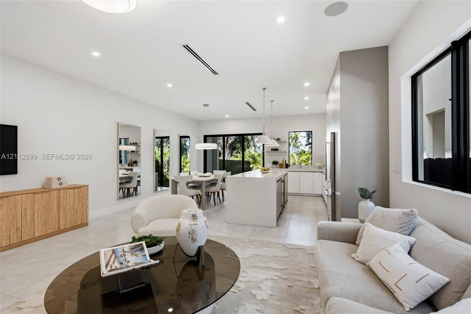 2747 SW 23rd Terrace, Miami, FL 33145 Open-concept living space featuring a central kitchen island with stone-finish waterfall countertop, large-format tile flooring, recessed ceiling lighting, and sliding glass doors