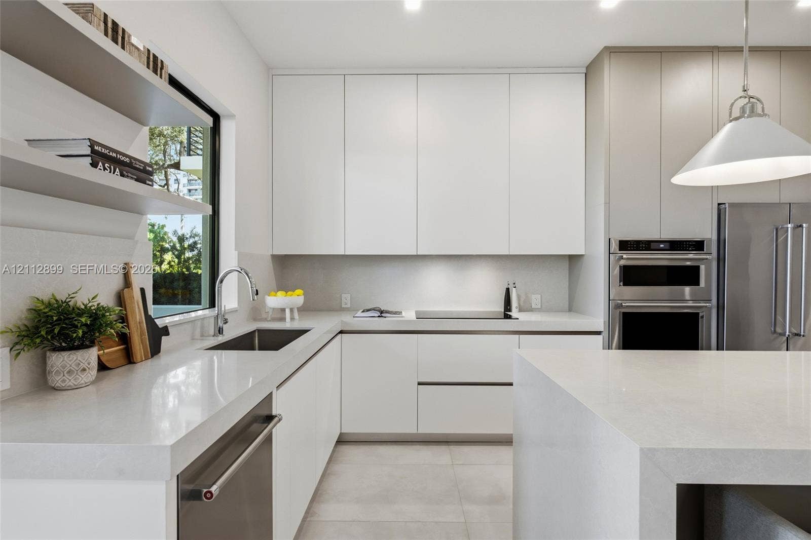 2747 SW 23rd Terrace, Miami, FL 33145 Modern kitchen featuring flat-panel cabinetry, light-toned stone countertops, built-in stainless steel appliances, dual open floating shelves, and an oversized island