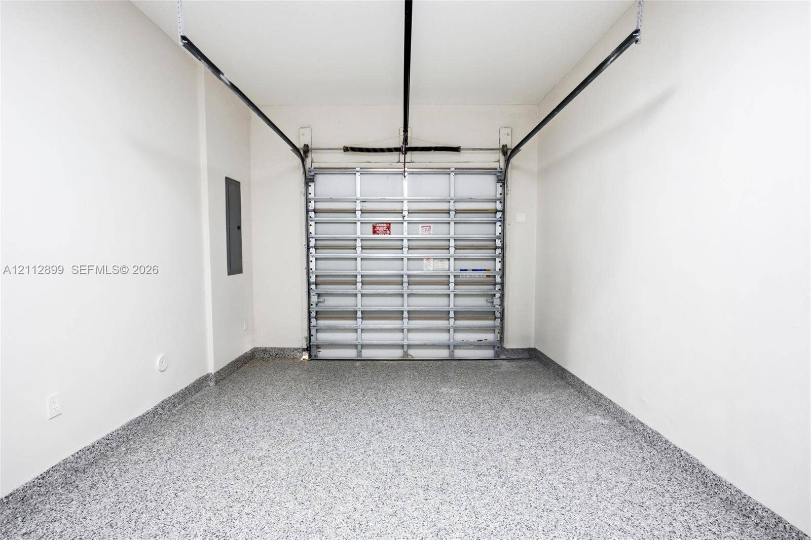 2747 SW 23rd Terrace, Miami, FL 33145 Enclosed garage space featuring a metal overhead door, seamless speckled epoxy flooring, and crisp white wall finishes