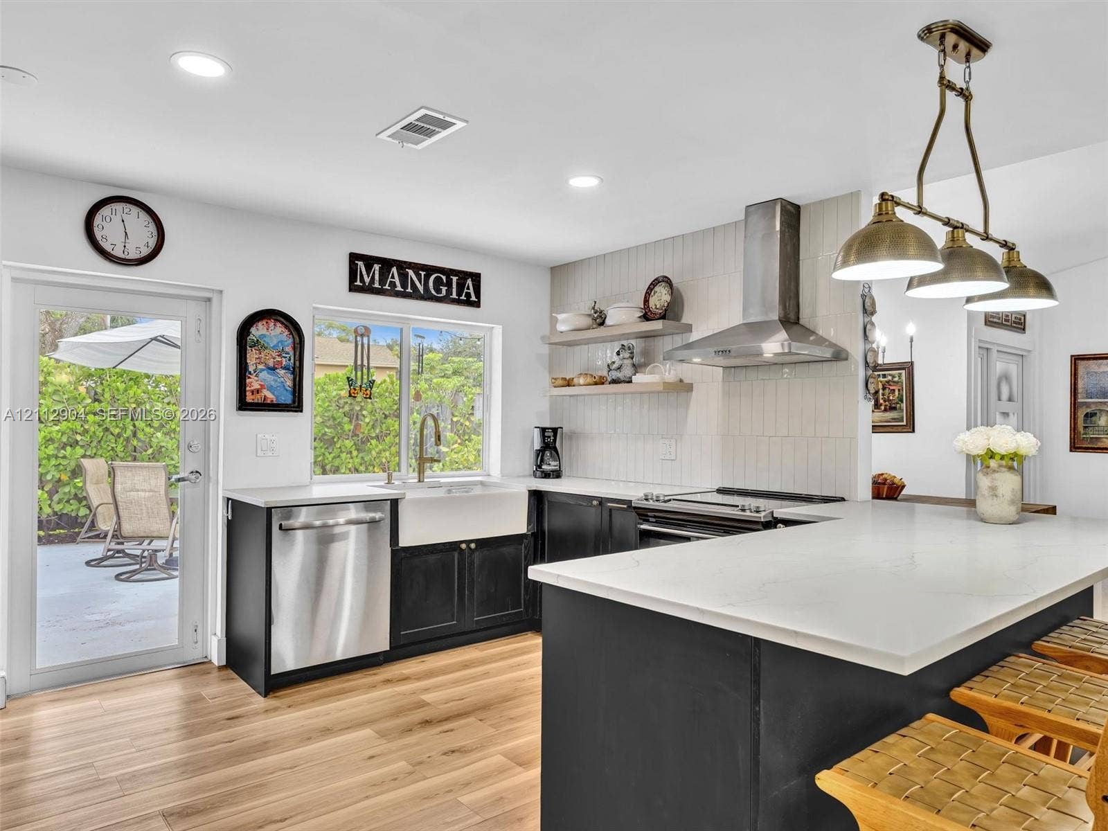76 Forest Circle, Cooper City, FL 33026 Kitchen featuring an expansive center island with stone countertop, stainless steel appliances, apron-front sink, vertical-tile backsplash, and open wood shelving