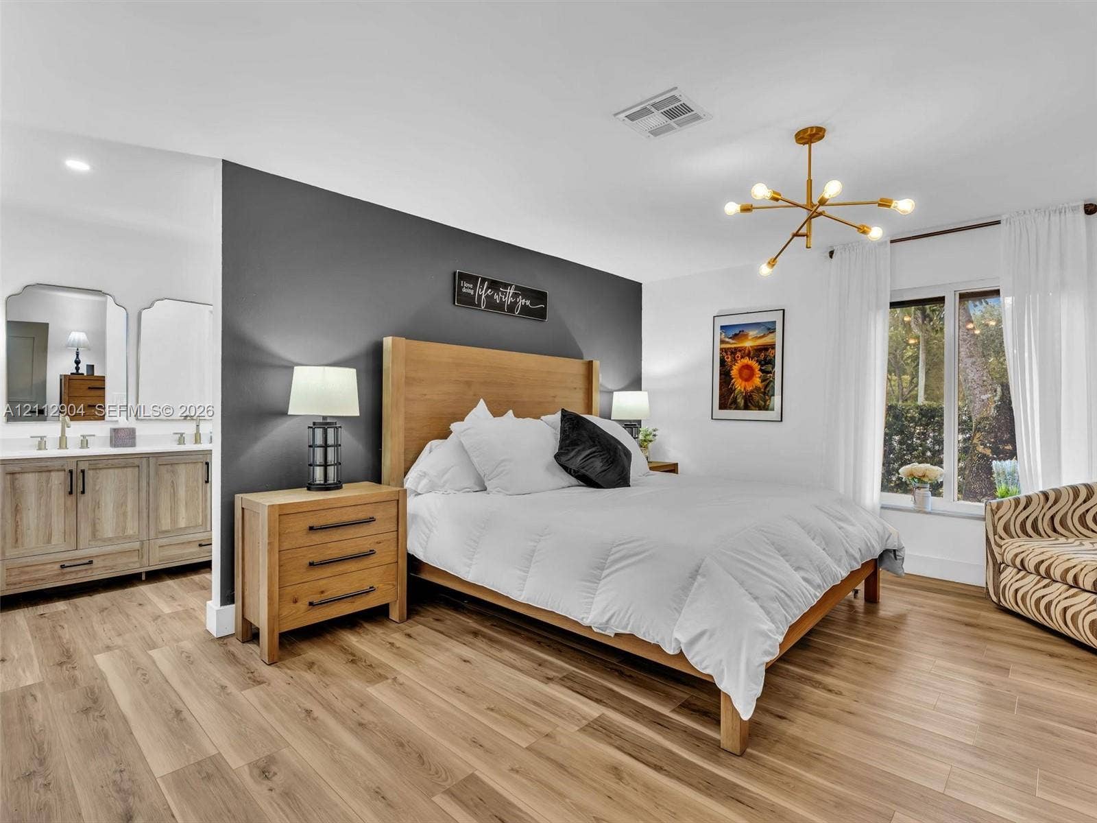 76 Forest Circle, Cooper City, FL 33026 Wood-finish flooring, charcoal accent wall, multi-arm brass finish chandelier, and dual-sink vanity with framed mirrors