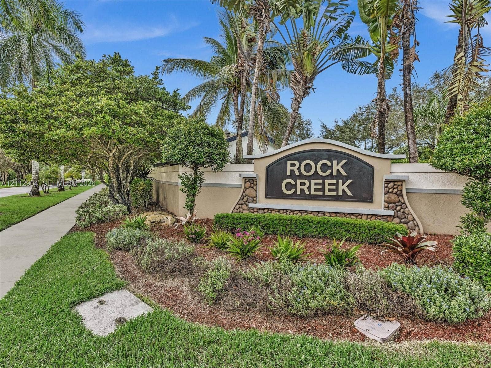76 Forest Circle, Cooper City, FL 33026 Community signage featuring stone masonry accents, professionally manicured landscaping, and mature palm trees