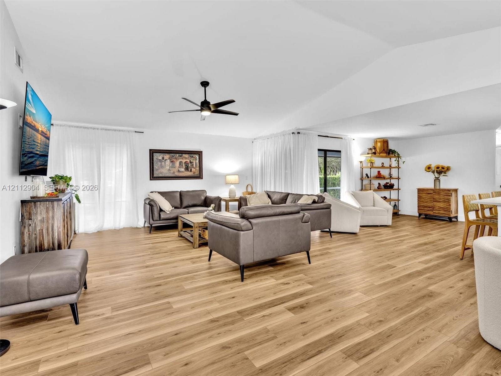 76 Forest Circle, Cooper City, FL 33026 Vaulted ceilings, wood-finish flooring, and a contemporary ceiling fan in an open-concept interior with expansive sliding glass doors